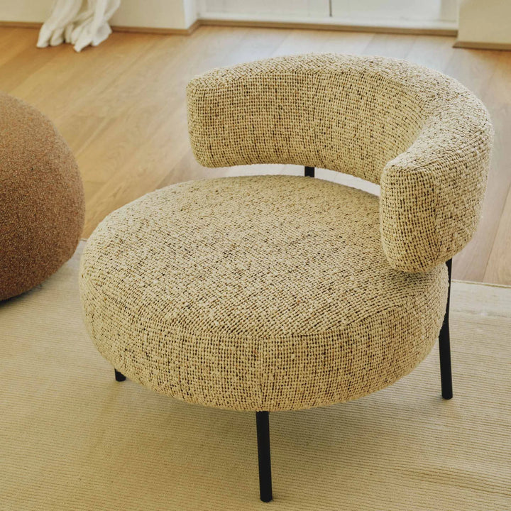 Beige textured chair with black legs on a wooden floor