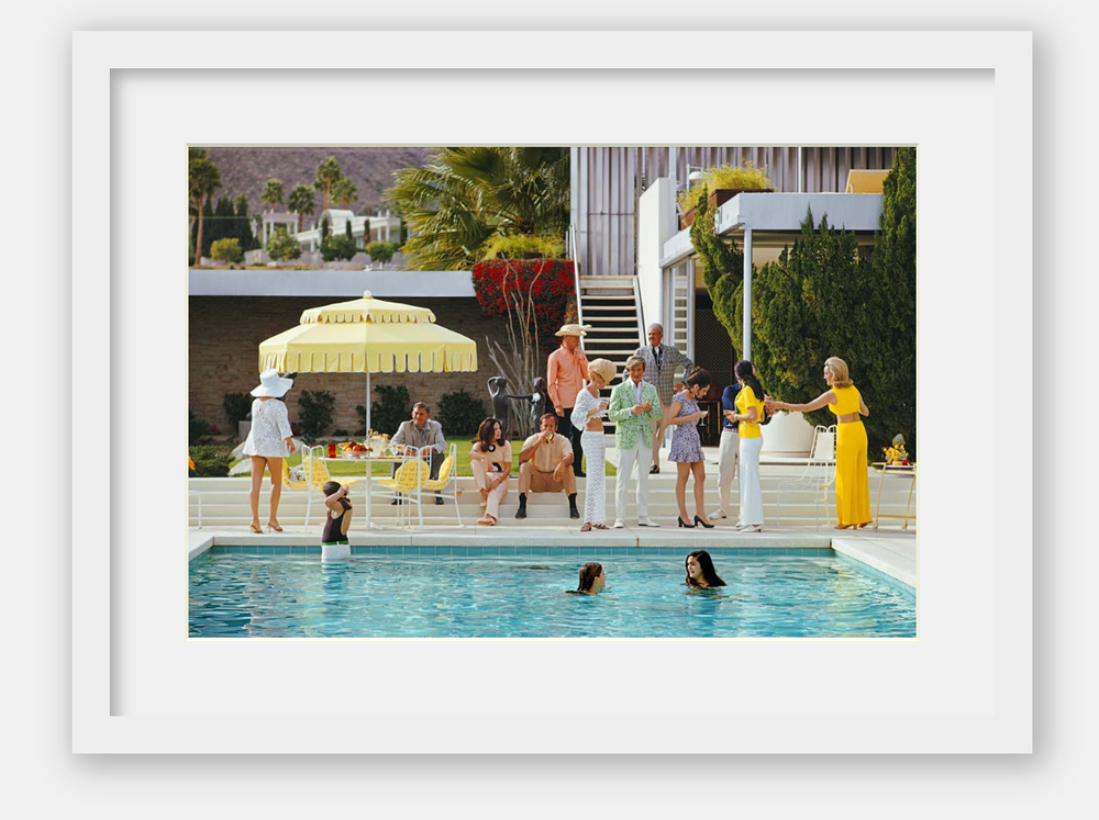 Framed artwork of a pool party scene with people around a pool and a yellow umbrella.