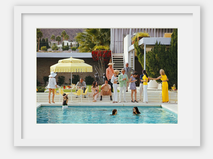 Framed artwork of a pool party scene with people around a pool and a yellow umbrella.