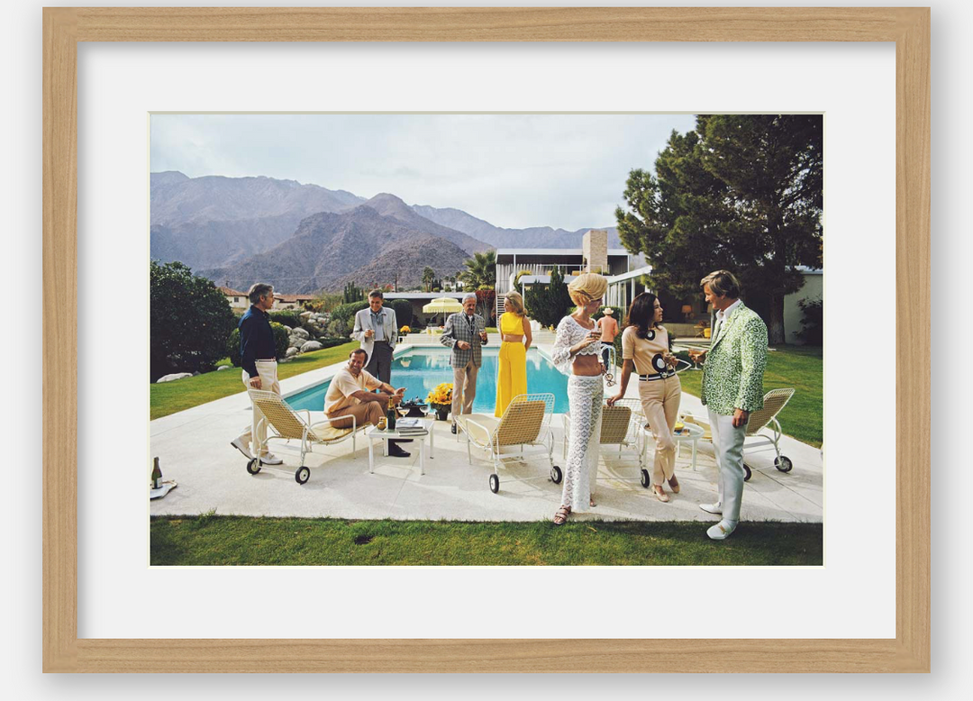 People socializing by a pool with mountains in the background