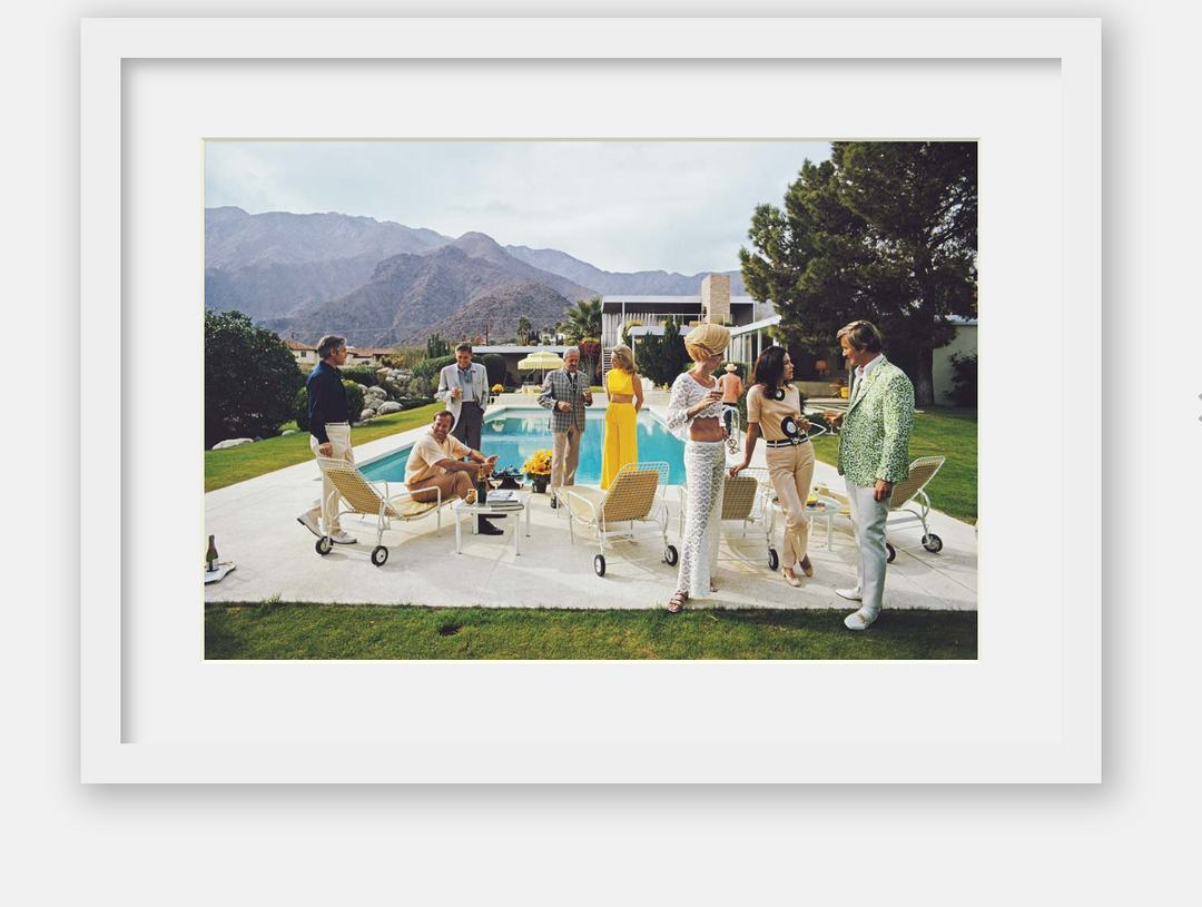 People gathered around a pool with mountains in the background