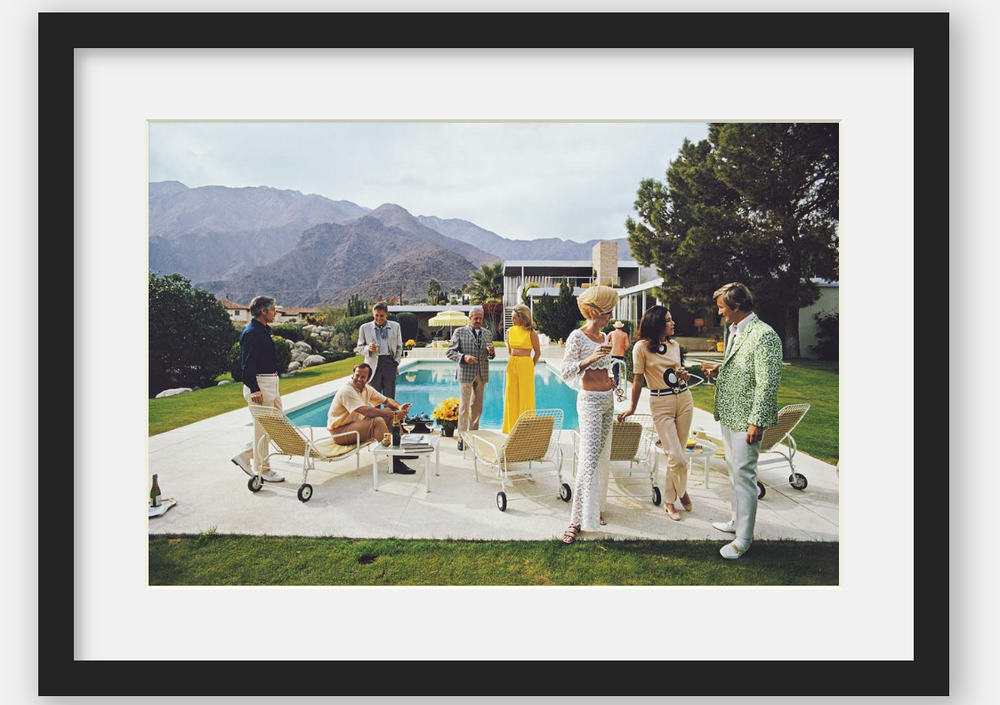 People gathered around a pool with mountains in the background